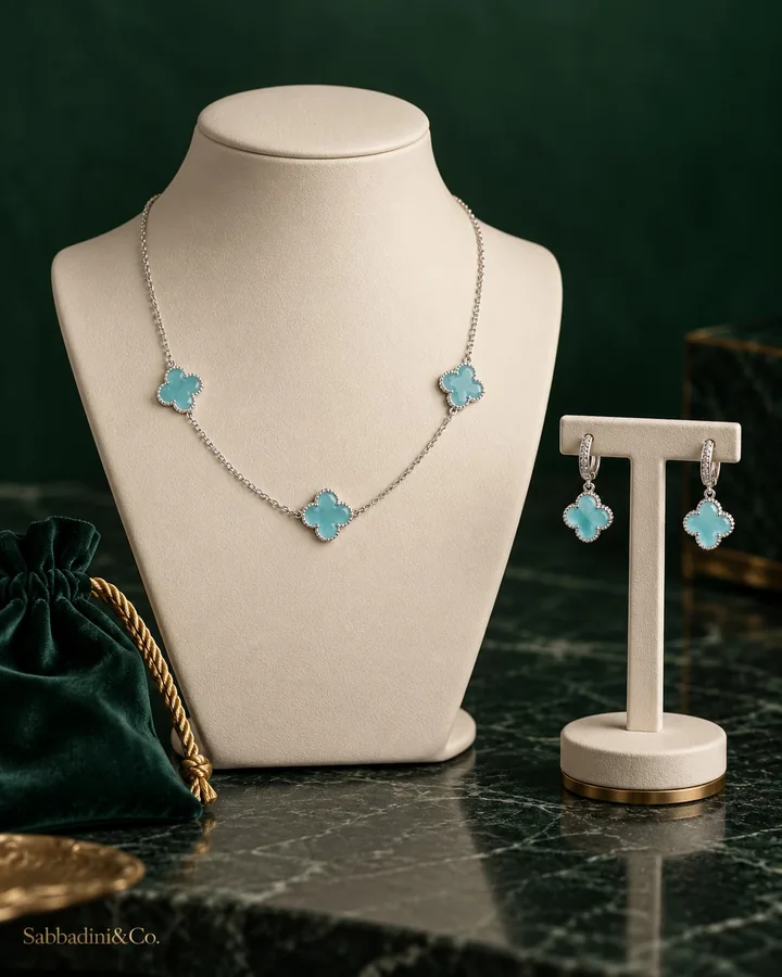 Conjunto Sabbadini Origins com colar e brincos de trevo azul-água em mostruário.